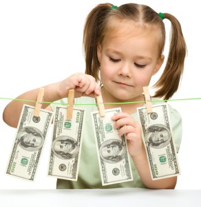 Cute little girl is playing with paper money - dollars, isolated over white